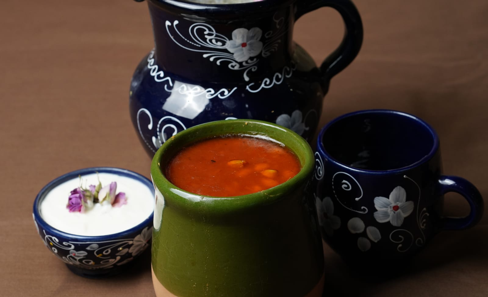دیزی سنگی داغ با نخود و لوبیا در ظرف سفالی، کنار ماست و پارچ دوغ؛ رستوران باباحاجی قم